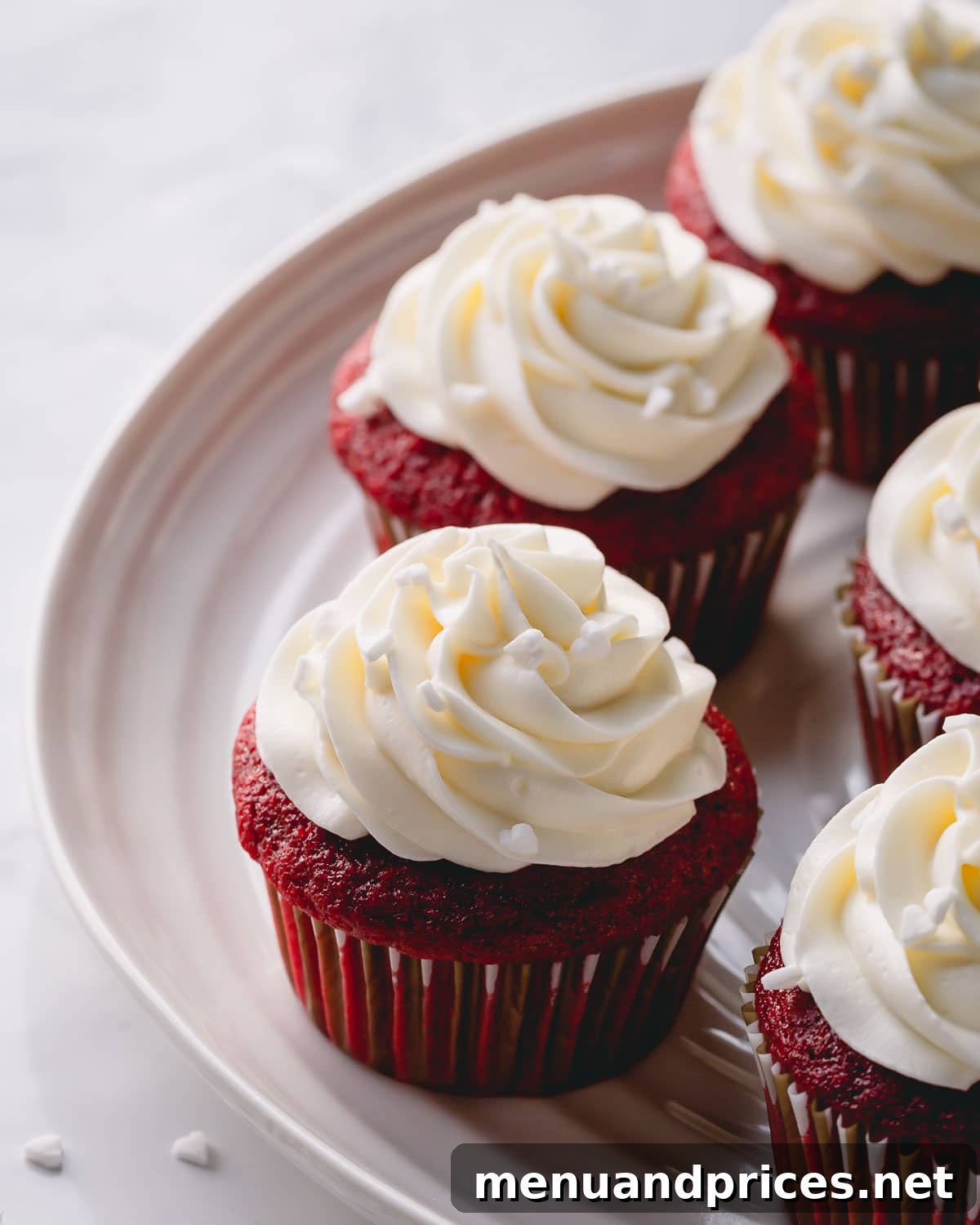 Velvet Dream Cupcakes 3 A platter brimming with perfectly baked red velvet cupcakes, each topped with a generous swirl of white cream cheese frosting.