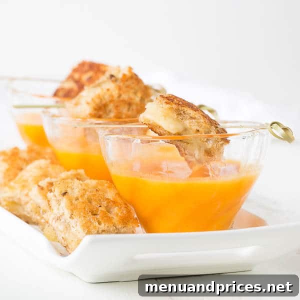 Velvety 5-Ingredient Butternut Squash Soup 2 A vibrant bowl of creamy butternut squash soup, garnished with crispy bacon bits, served alongside golden Fontina grilled cheese triangles, capturing the essence of a perfect fall meal.
