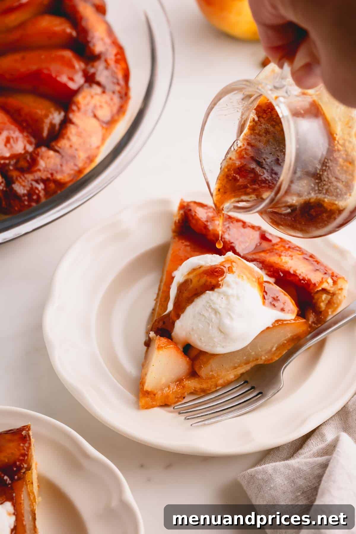 Close-up of pear syrup being poured elegantly over a slice of French pear pie topped with a scoop of vanilla ice cream, creating a mouth-watering presentation.