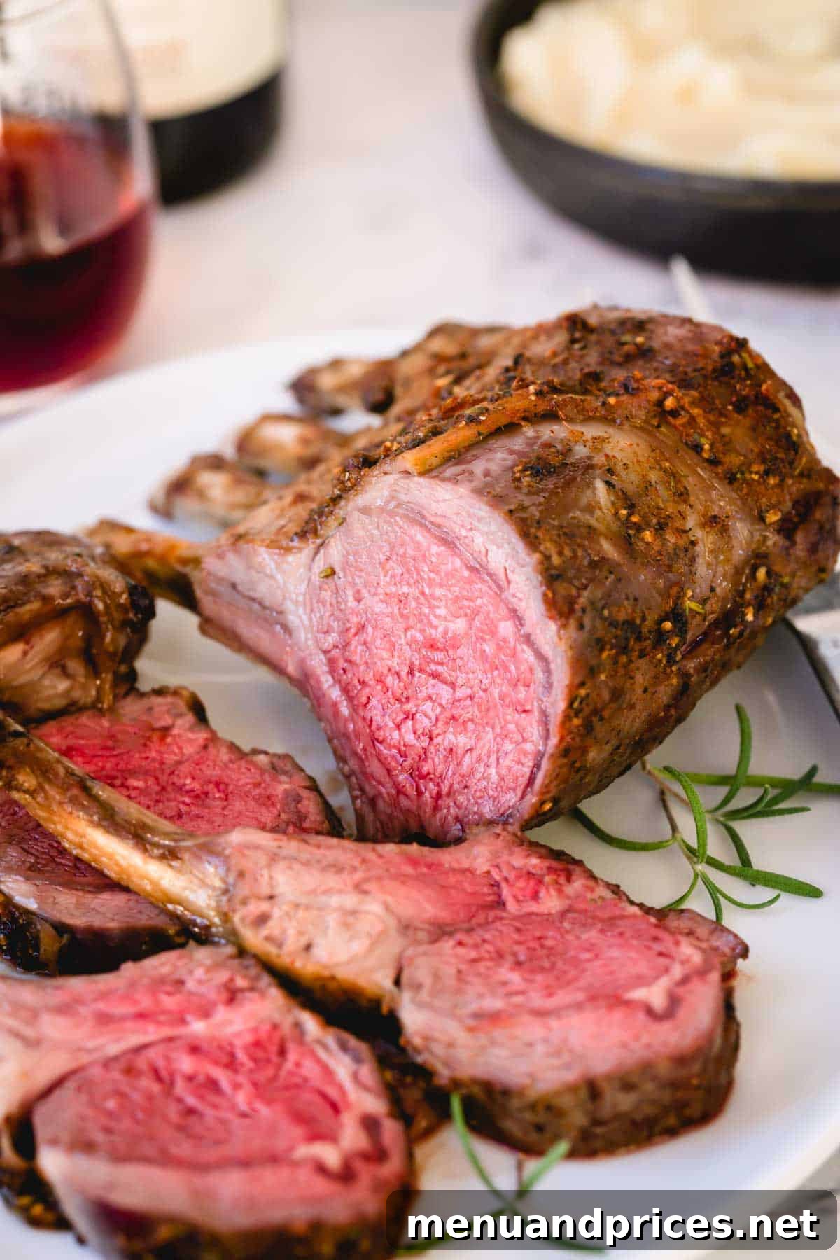 Herb-Crusted Lamb Rack 2 Perfectly sliced roasted rack of lamb on a pristine white platter, garnished with fresh rosemary and ready to serve.