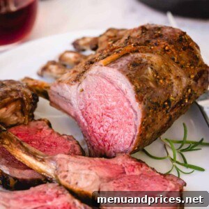 Sliced roasted rack of lamb on a white platter, garnished with fresh herbs and ready to be enjoyed.