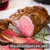 Herb-Crusted Lamb Rack 8 Another close-up view of perfectly sliced roasted rack of lamb on a white platter, showcasing its beautiful tender interior and golden crust.