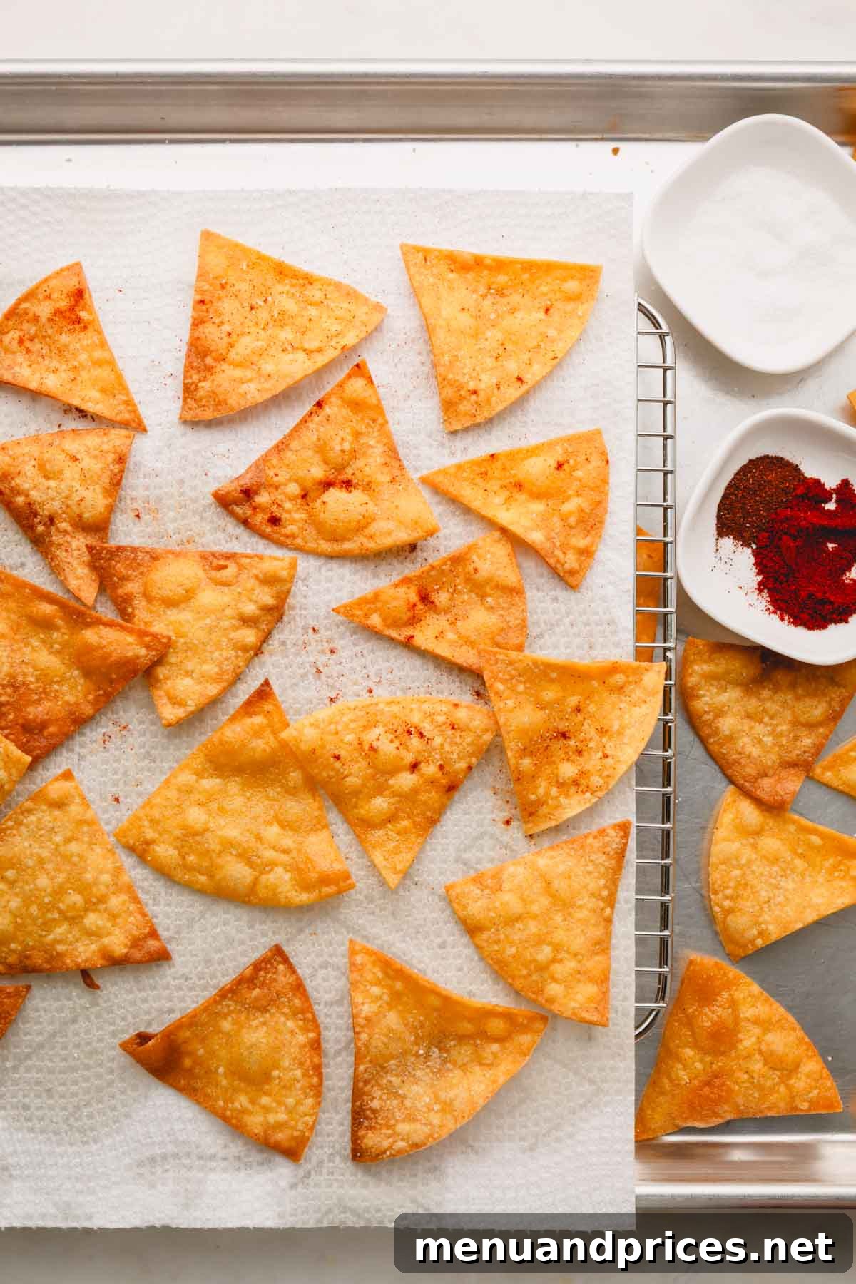 Zesty Handcrafted Tortilla Chips 8 Freshly fried and seasoned tortilla chips resting on paper towels over a wire rack to drain excess oil.