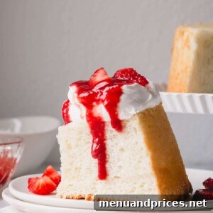 A slice of angel food cake topped with whipped cream and strawberry sauce.