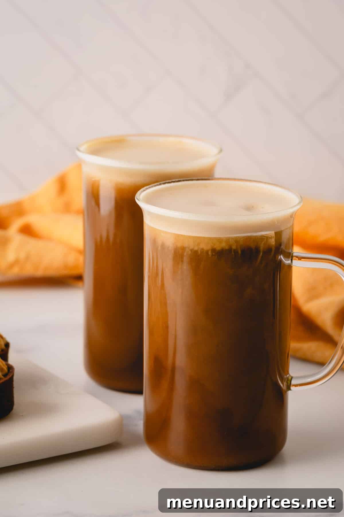 Two glass mugs full of coffee topped with pumpkin mousse.