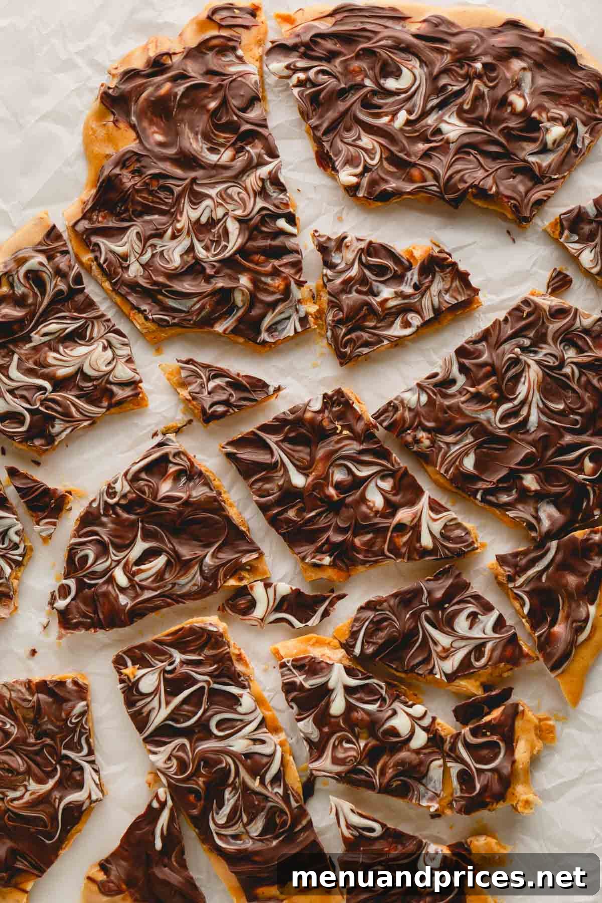 Gourmet Chocolate Peanut Brittle 11 An overhead view of finished chocolate peanut brittle pieces resting on parchment paper, highlighting their glossy chocolate top and crunchy base.