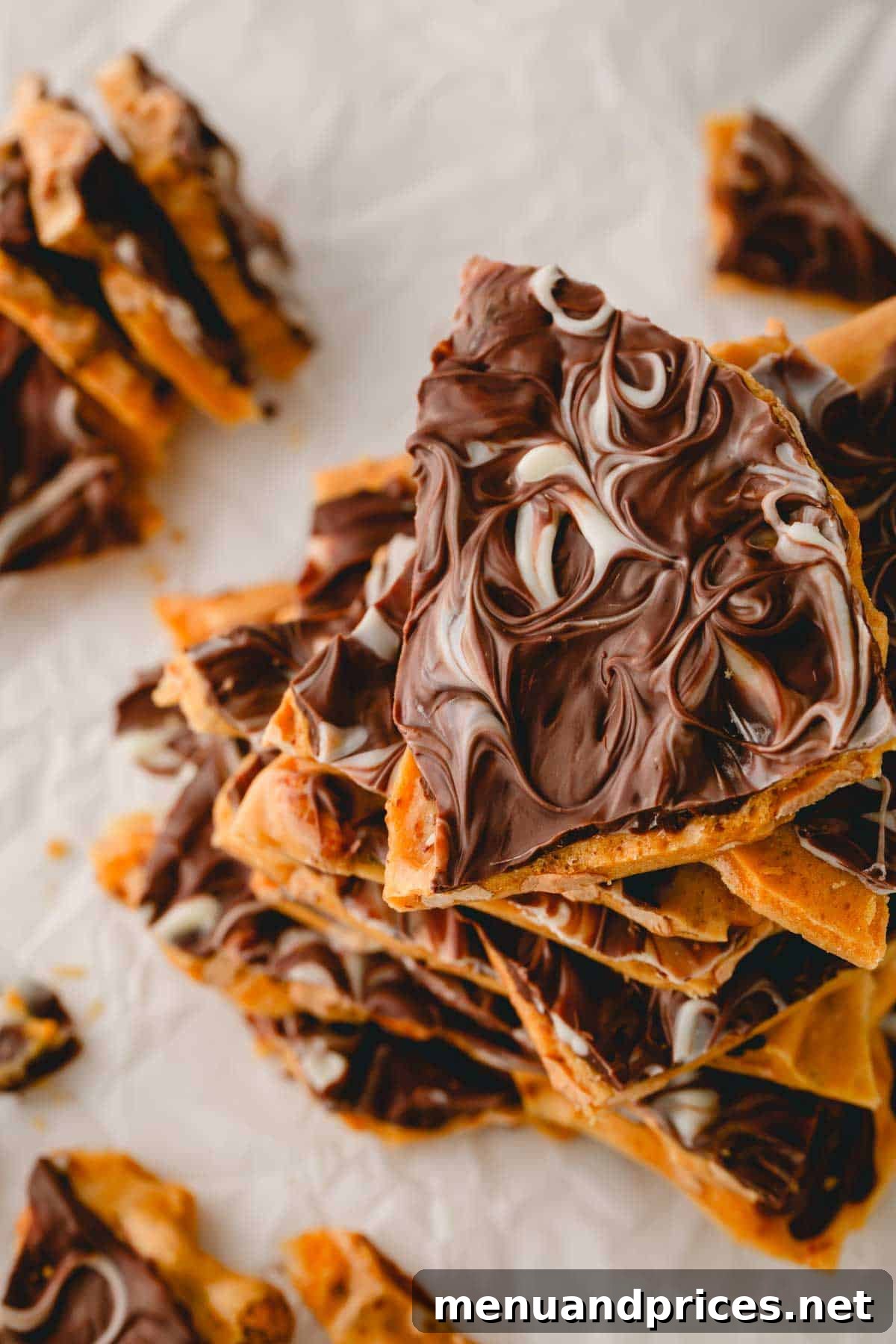 Gourmet Chocolate Peanut Brittle 4 Overhead shot of chocolate peanut brittle pieces adorned with elegant white chocolate swirls, adding a sophisticated touch.