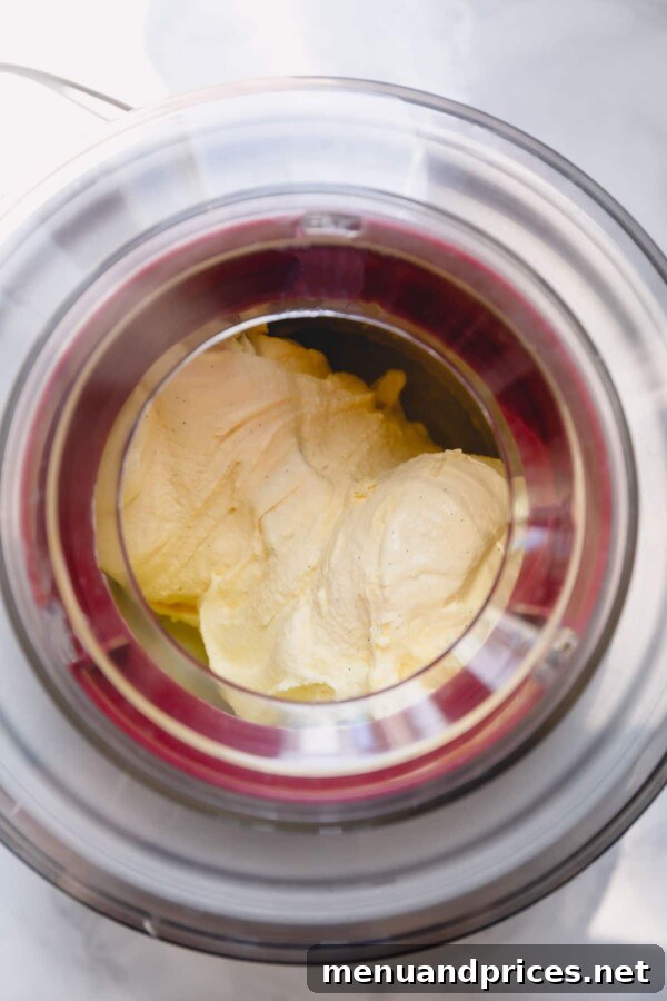 Dreamy Homemade Vanilla Ice Cream 9 Vanilla ice cream actively churning within an ice cream maker, showcasing its creamy transformation.