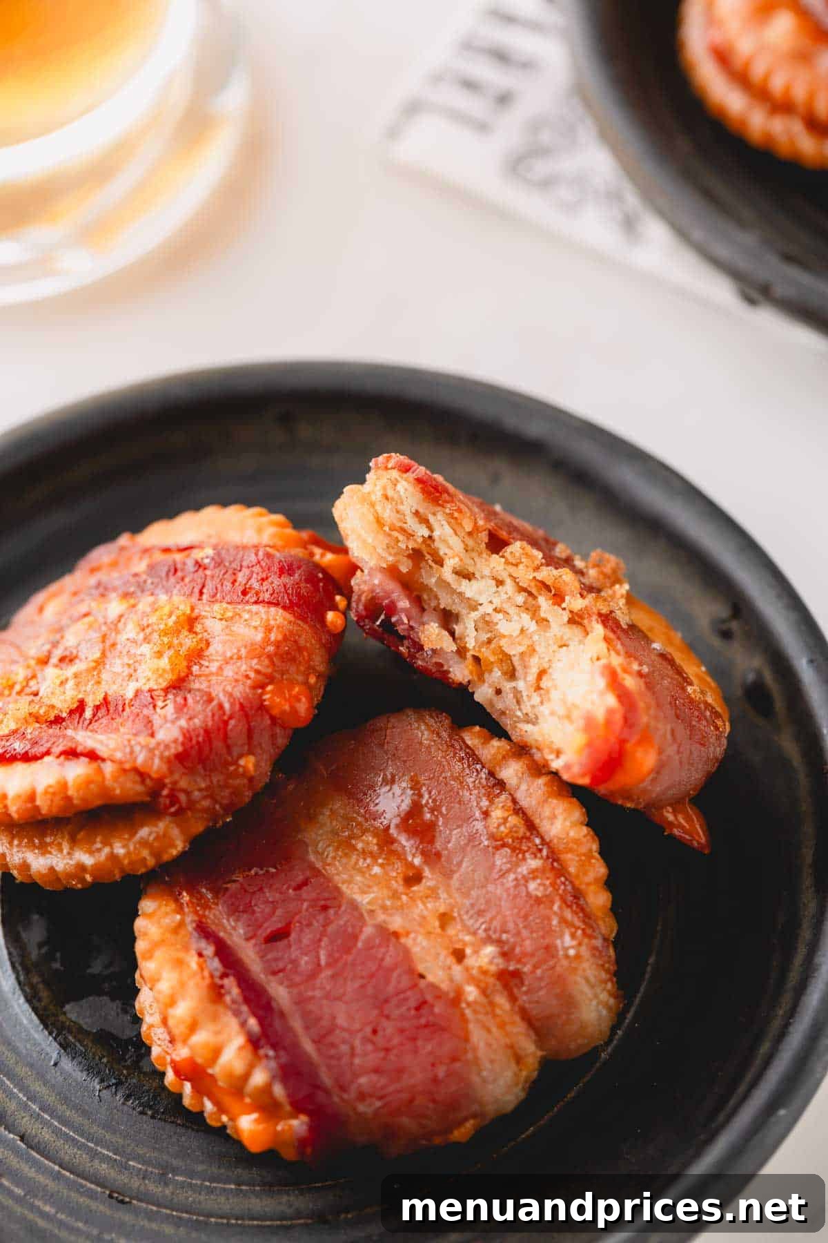 Bacon Cheddar Crisps 10 A trio of perfectly baked cheesy bacon crackers artfully arranged on a plate, with one cracker revealing a delicious bite taken out.