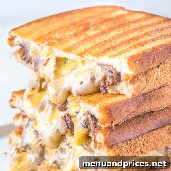 Full view of two Philly Cheesesteak Grilled Cheese sandwiches on a cutting board