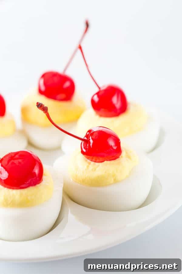 Tropical Pina Colada Deviled Eggs 11 Sweet deviled eggs beautifully arranged on a white serving platter, each topped with a glistening maraschino cherry.