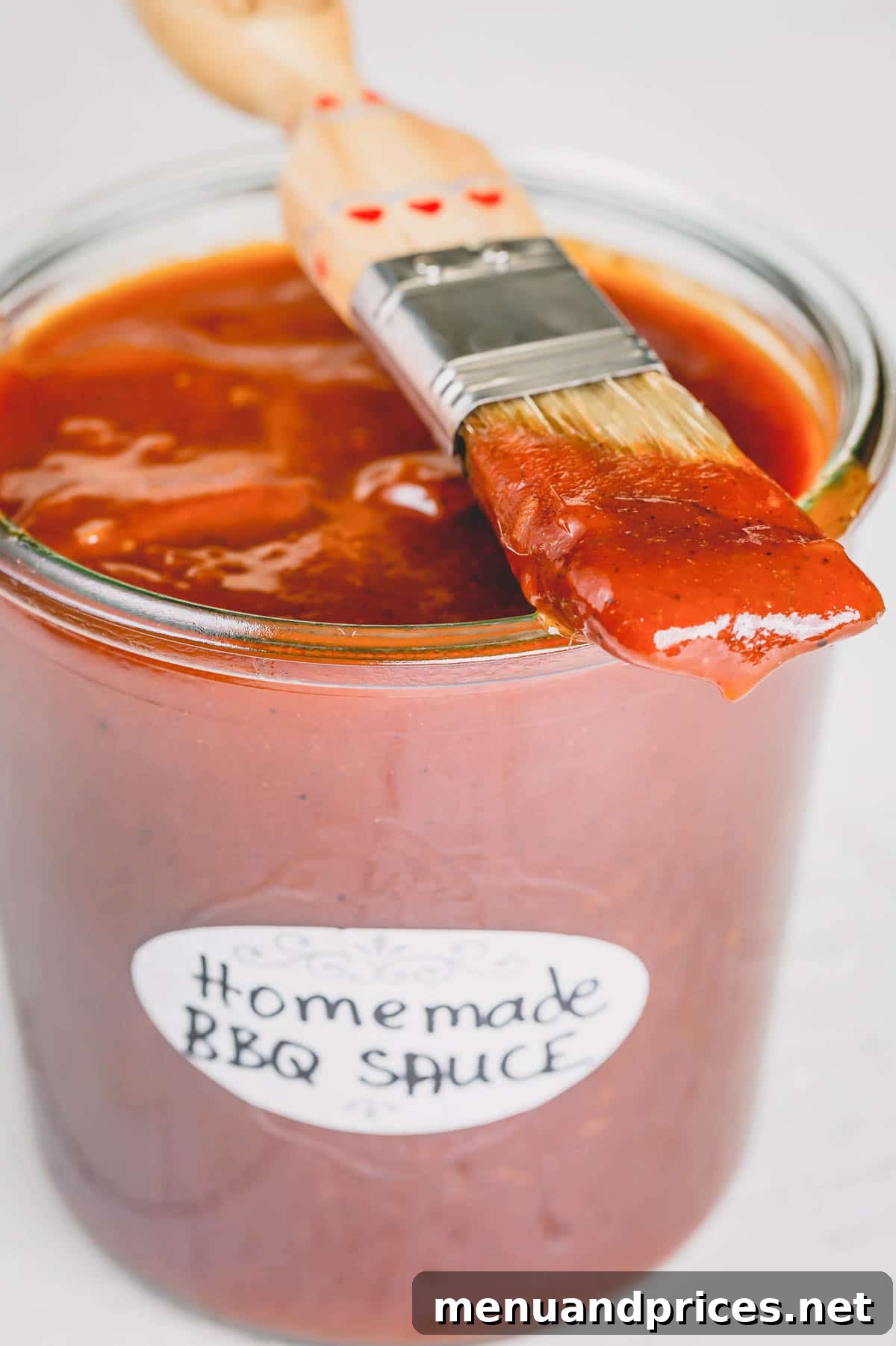 Crafting Your Perfect Homemade BBQ Sauce 2 A jar of homemade BBQ sauce with a basting brush, ready for summer grilling.