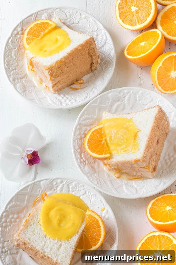 Closeup of the Orange Blossom Angel Food Cake with its vibrant orange curd, showing the soft, airy texture of the cake.