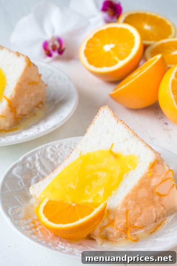 Sliced Orange Blossom Angel Food Cake, showcasing its perfect rise and airy texture, adorned with a generous serving of homemade orange curd.