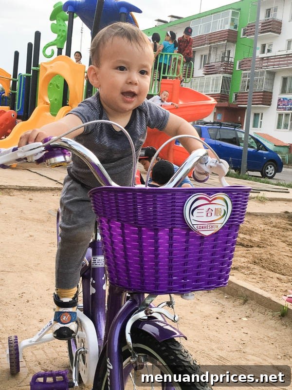 Grant's Inaugural Mongolian Expedition Part One 10 Baby Grant humorously trying to ride an oversized girl's bicycle in Mongolia, with an adult watching