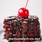 Chocolate cherry cake slice topped with chocolate fudge and maraschino cherry.