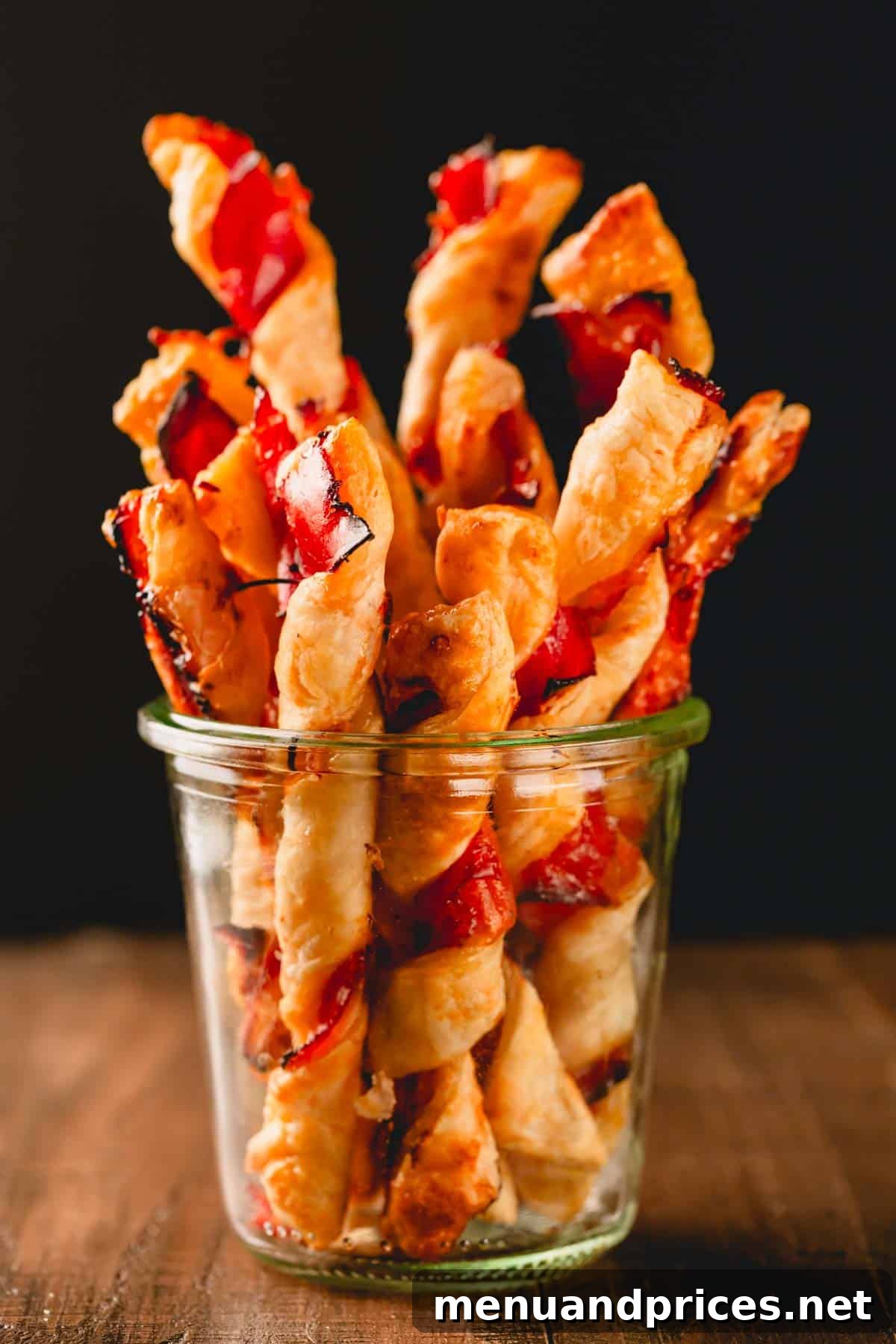 Golden Savory Spirals 11 A glass jar full of baked puff pastry twists with prosciutto.
