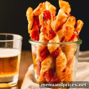 Savory puff pastry twists in a glass cup.