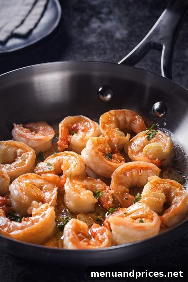 Fresh garlic slices infusing butter in a skillet, creating an aromatic base for the shrimp.