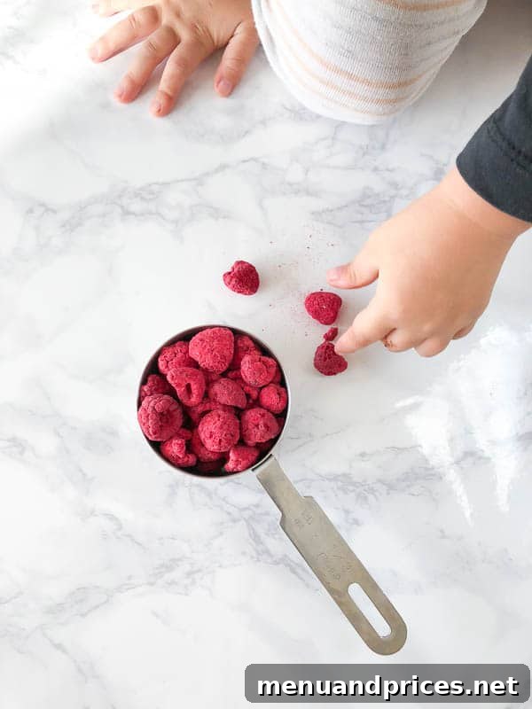 Culinary Chaos with a Curious Kid 12 Toddler boy Grant reaching with delight for a bowl overflowing with his favorite freeze-dried raspberries during a busy photoshoot session
