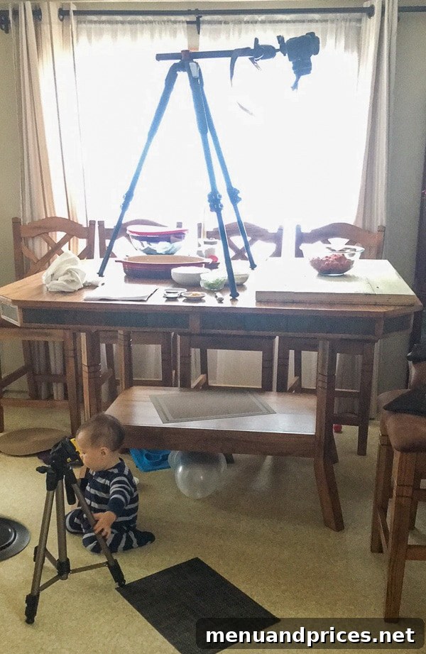 Culinary Chaos with a Curious Kid 3 Toddler boy Grant intently watching his mom film a video with a tripod and professional lighting setup next to a table laden with food