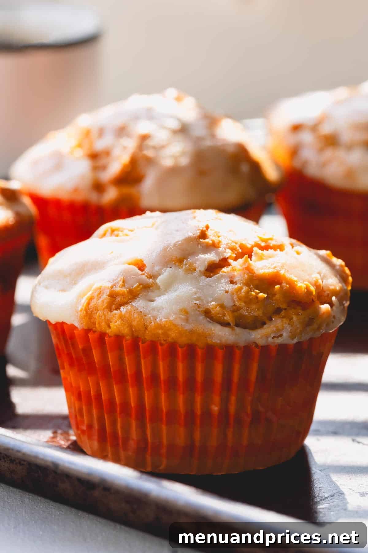 Cheesecake Swirl Pumpkin Muffins 2 Pumpkin cheesecake muffins in muffin liners, showcasing their golden tops and rustic appeal.