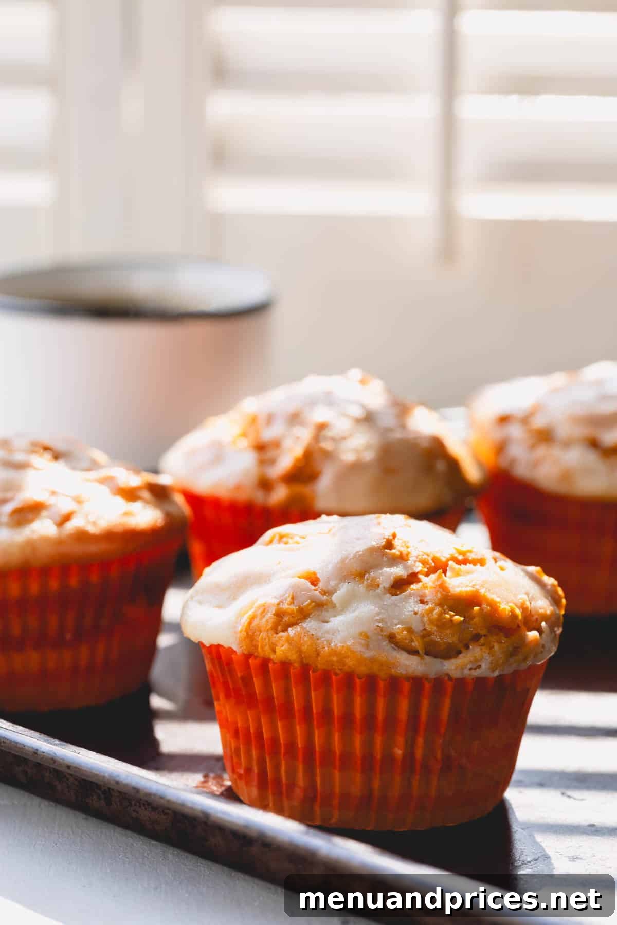 Cheesecake Swirl Pumpkin Muffins 7 A close-up shot of several pumpkin cheesecake muffins, freshly baked and nestled in their paper liners.