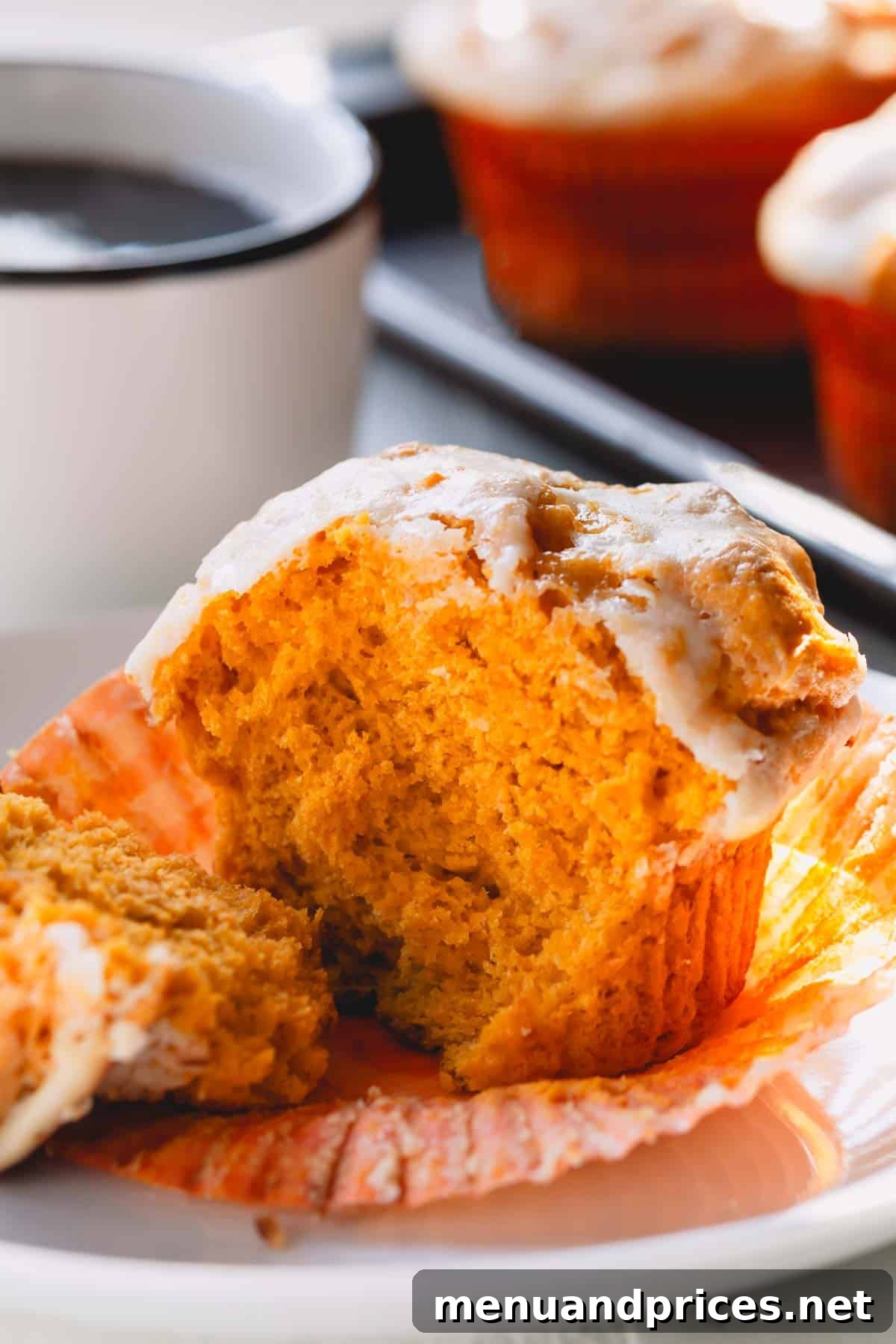 Cheesecake Swirl Pumpkin Muffins 8 A pumpkin muffin torn in half on a white plate, highlighting its moist interior and the creamy swirl.