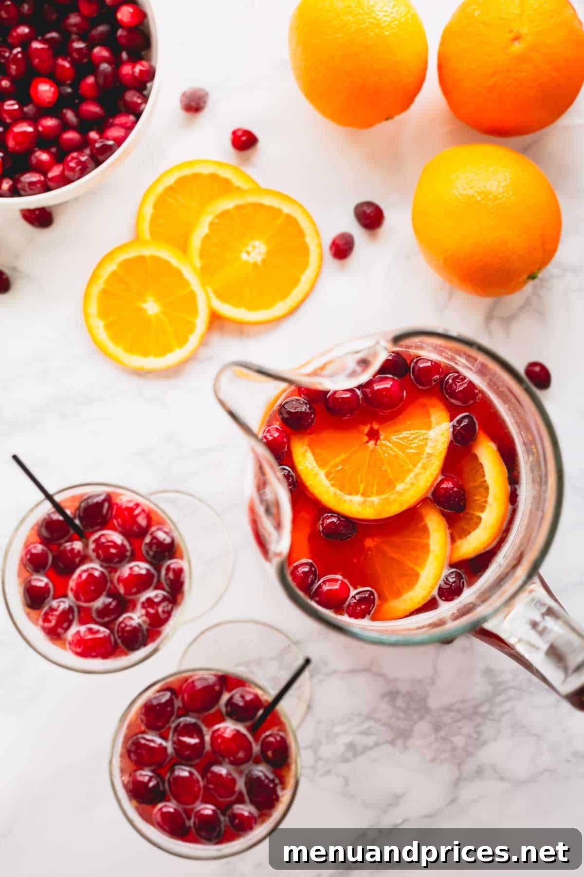 Overhead image of two glasses of orange cranberry spritzer next to a pitcher of the drink mix, inviting enjoyment.