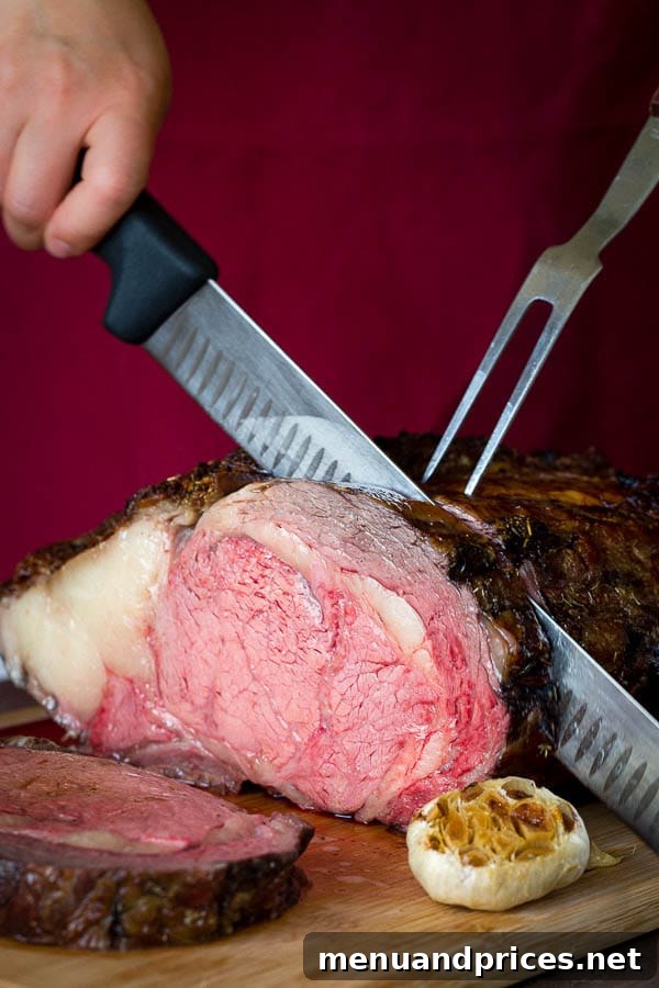 Signature Garlic Herb Crusted Boneless Prime Rib 7 Expertly slicing a large garlic herb crusted prime rib into thick, even pieces, showcasing its perfectly cooked interior.