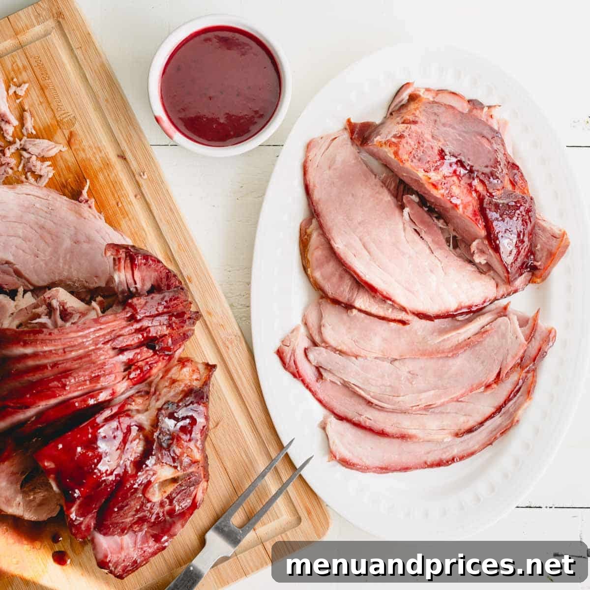 Overhead image of glazed spiral ham on a wooden cutting board, with a serving platter and a bowl of the delicious glaze.
