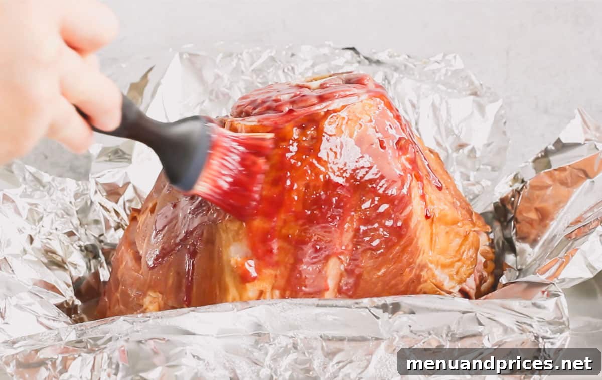 A spiral ham being brushed with the delicious raspberry mustard glaze for the first time, ready for its final roast.