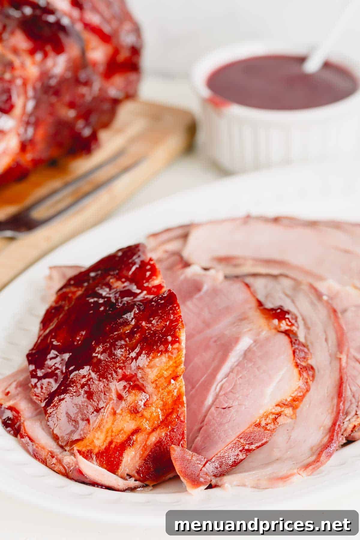 A platter of beautifully sliced spiral ham adorned with the 2-ingredient raspberry mustard glaze, showcasing its tenderness.