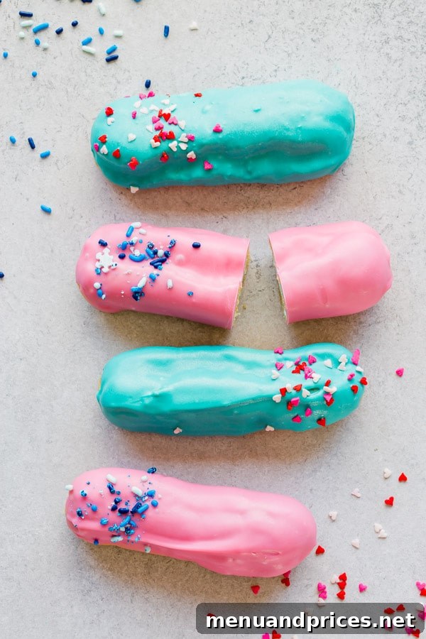 A selection of decorated gender reveal eclairs, some topped with pink frosting and others with blue, ready for the big reveal. #EclairRecipe #GenderRevealPartyIdeas #HomemadeTreats
