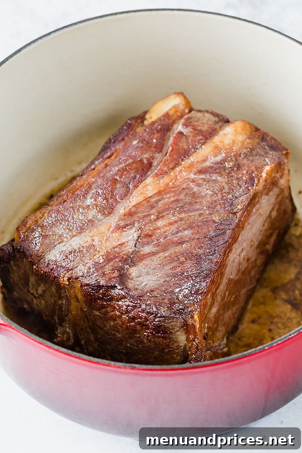 No-Fuss Pot Roast 4 A close-up shot of a chuck roast being seared in a hot Dutch oven, showing the golden-brown crust forming, which is vital for developing rich flavors in pot roast.