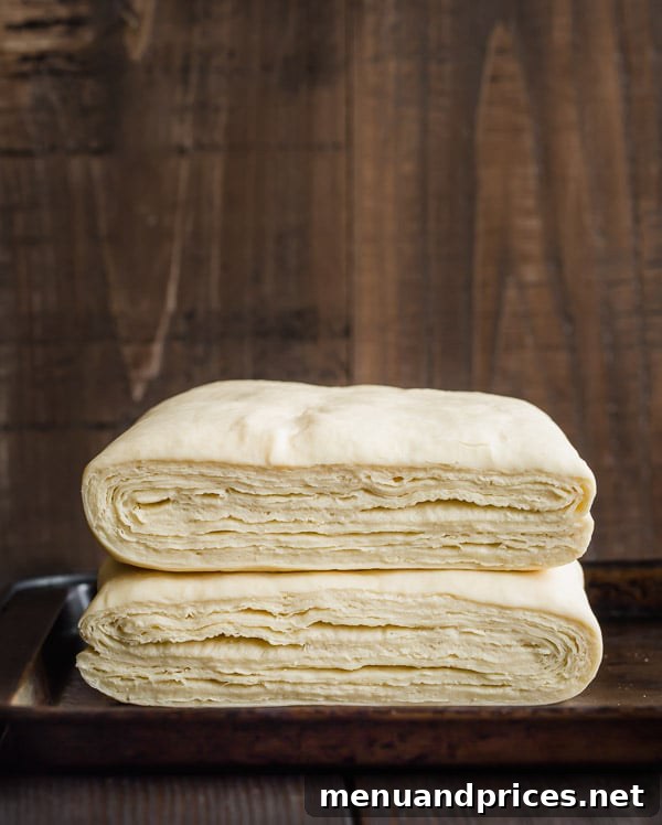 Detailed shot of hundreds of delicate and distinct layers in a block of homemade croissant dough, showcasing the impressive results of a successful lamination technique.