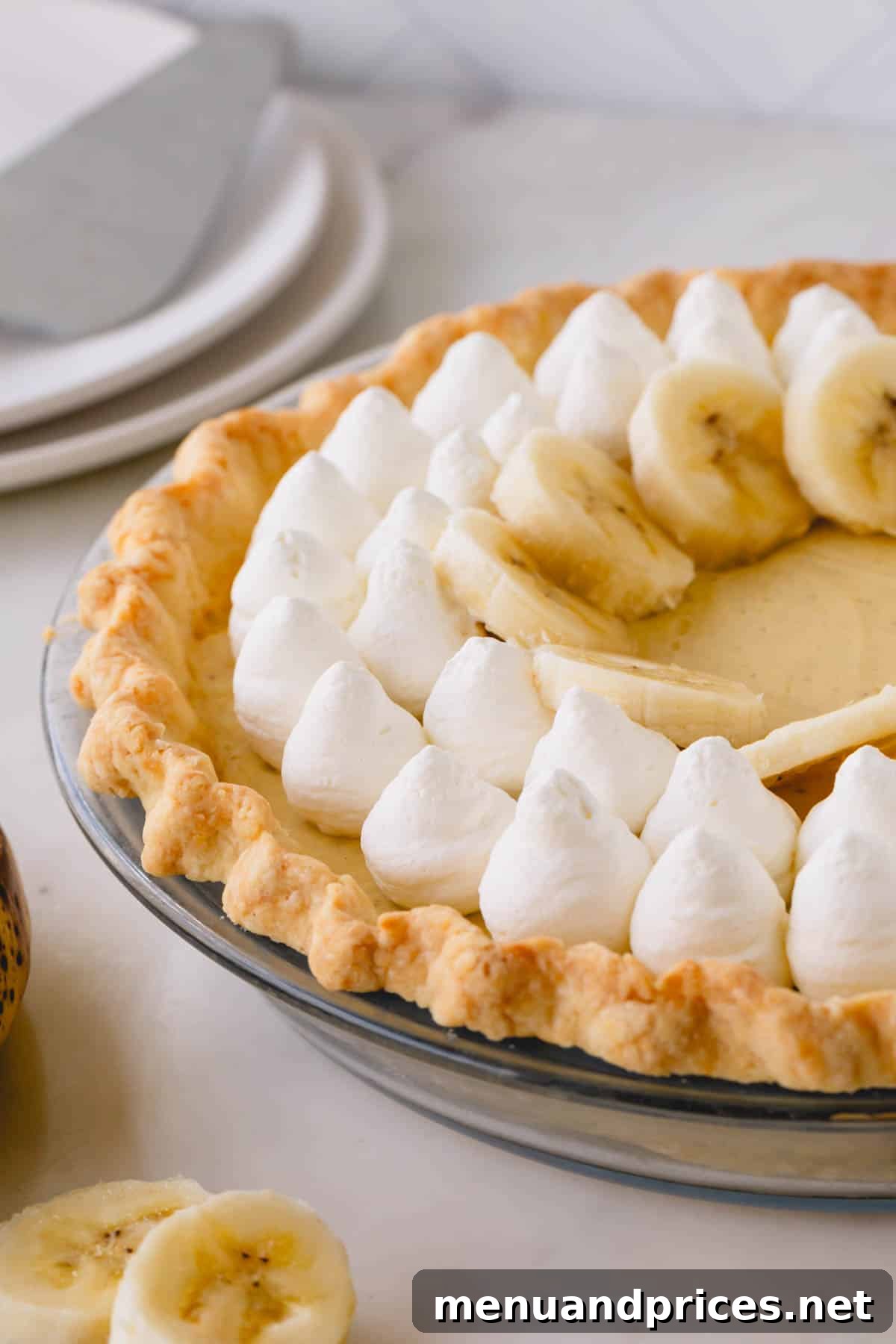 Luscious Banana Dream Pie 2 Banana cream pie decorated with dollops of whipped cream and banana slices, showcasing its elegant presentation.