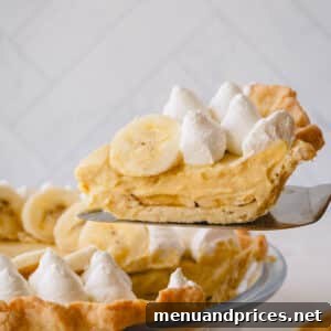 A slice of banana cream pie lifted up from the whole pie.