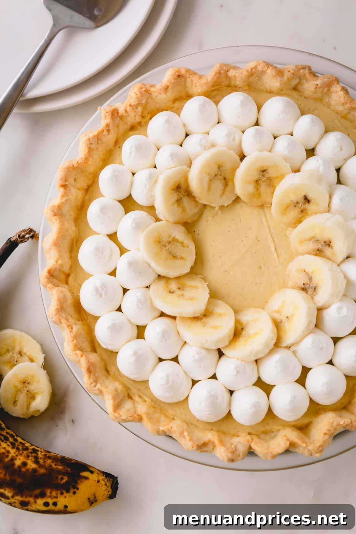 Luscious Banana Dream Pie 9 The fully assembled and decorated banana cream pie, adorned with elegant dollops of whipped cream and fresh banana slices, ready to be served.