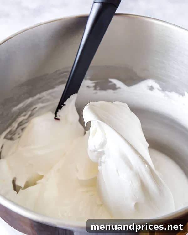 Meringue batter for Pavlova cake at stiff peaks, showcasing its glossy, firm texture.