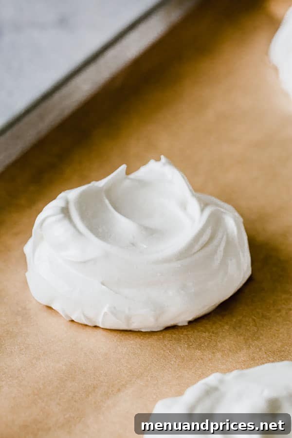 Meringue shaped into mini nests on a baking sheet, ready for baking.