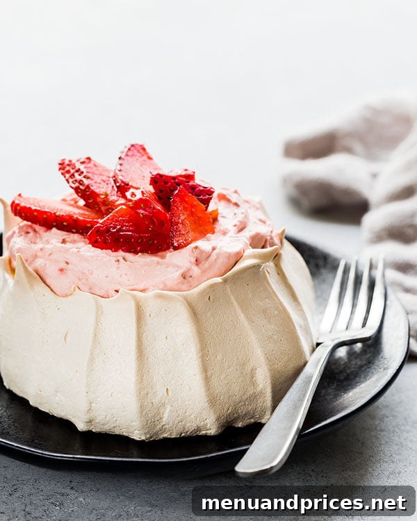 A mini strawberry pavlova on a plate, with a fork poised to take a bite, highlighting its soft interior.
