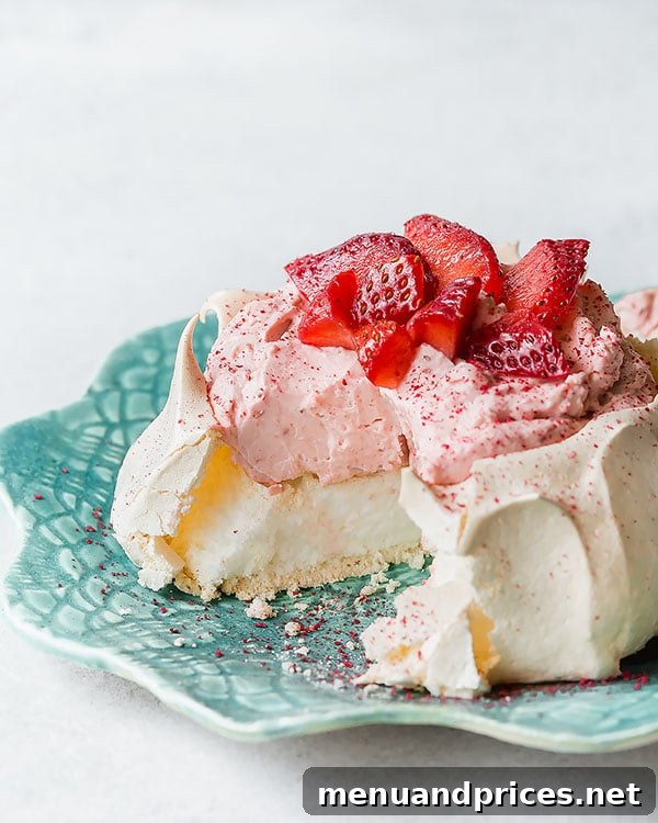 A mini strawberry pavlova with a slice removed, revealing its fluffy marshmallow center.