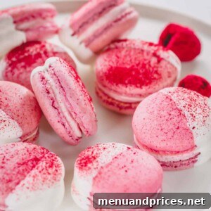 White chocolate dipped raspberry macarons arranged on a white platter.