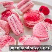 White chocolate dipped raspberry macarons arranged on a white platter.