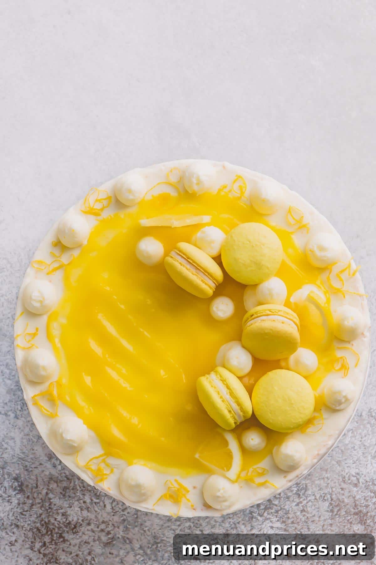 Close-up of the finished lemon layer cake, showcasing the beautiful lemon curd topping, piped buttercream dollops, and artfully placed lemon macarons, highlighting its intricate decoration.