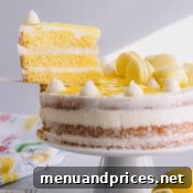 A close-up view of a perfectly sliced piece of lemon layer cake on a white plate.