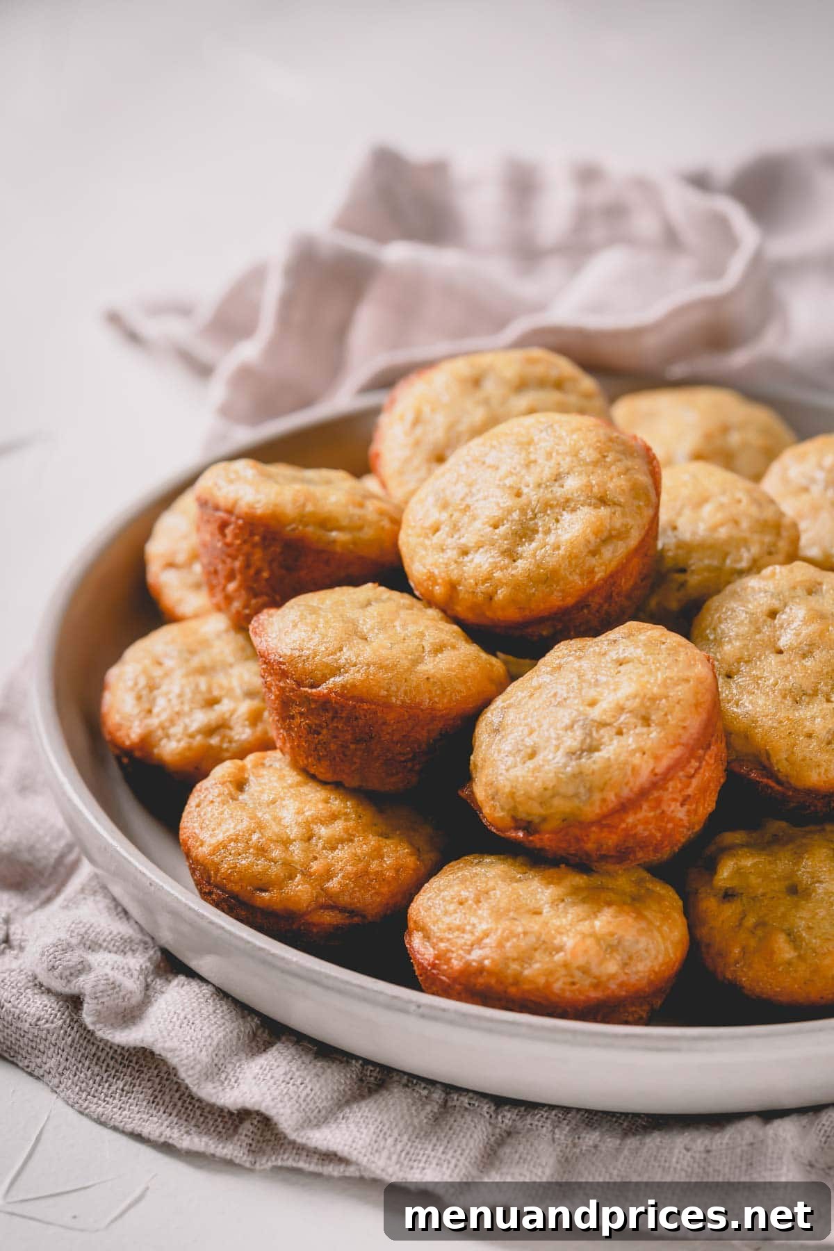 Deliciously Simple Banana Muffins 3 A plate featuring an assortment of mini banana muffins, showcasing their charming bite-sized appeal and golden-brown tops.