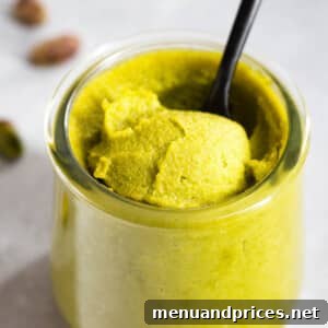 A glass jar of smooth pistachio paste.