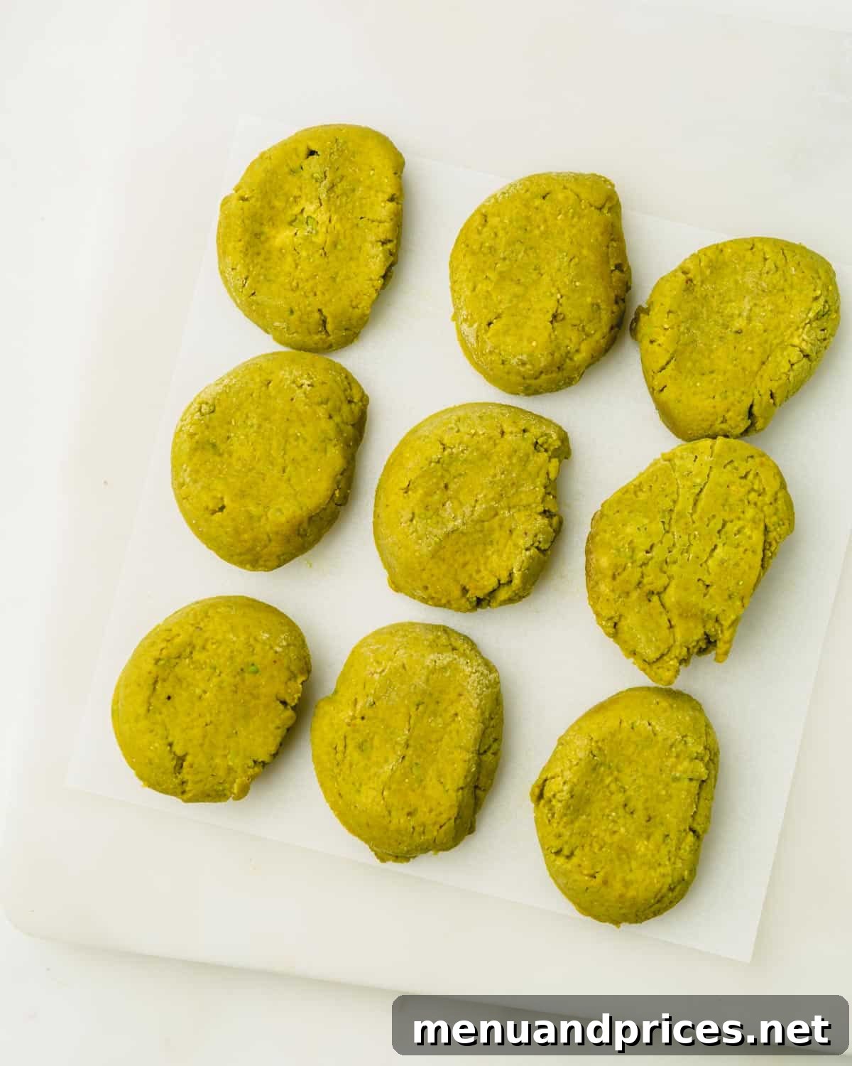Easy Homemade Pistachio Paste Recipe 10 Flat discs of pistachio paste arranged on white parchment paper, prepared for freezing.